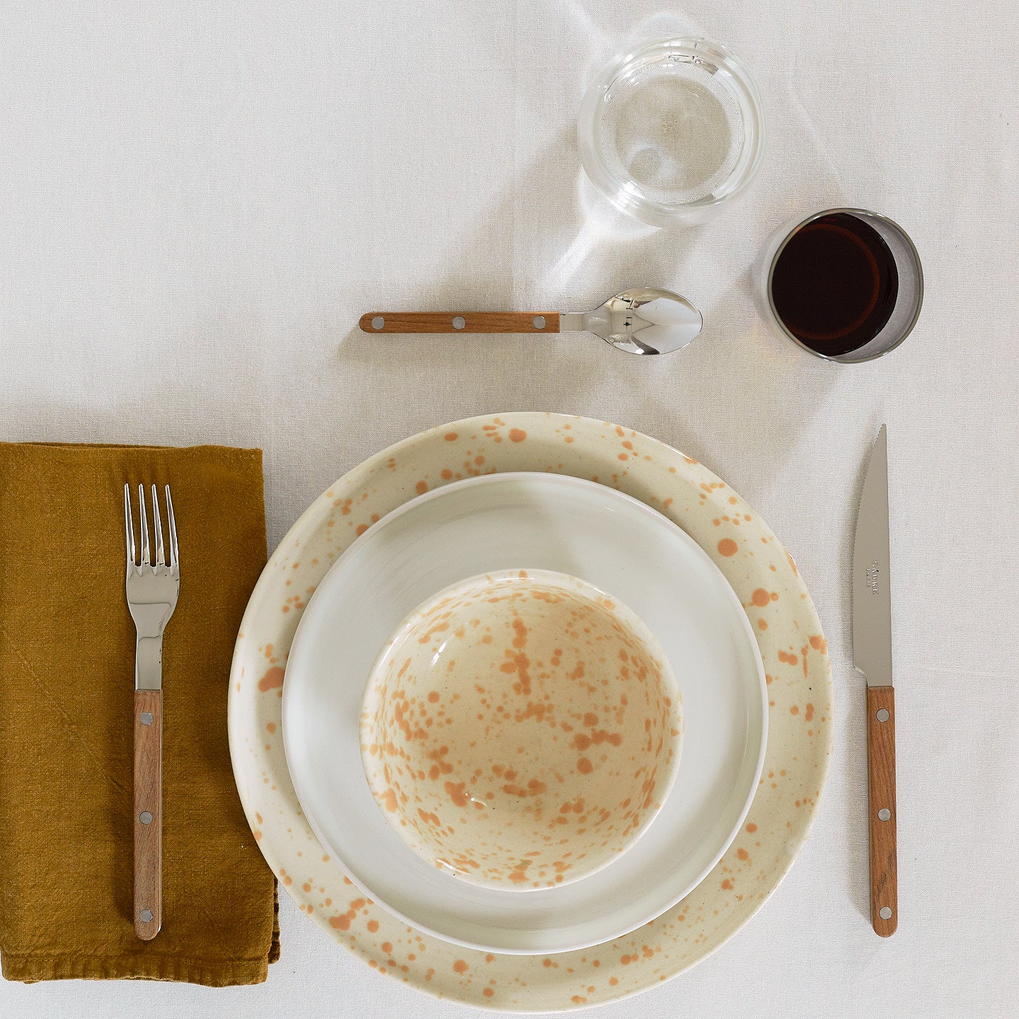 Place setting with Splatterware Plate in Latte on a white tablecloth.