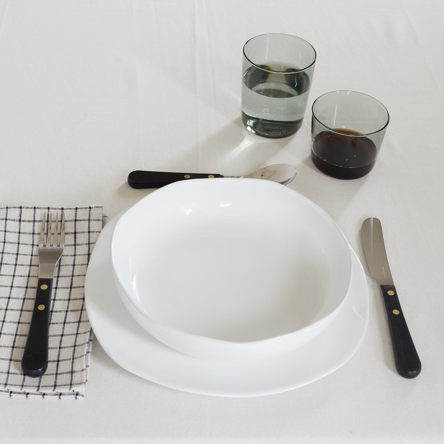 Placesetting of white Strata dinnerware on white tablecloth.