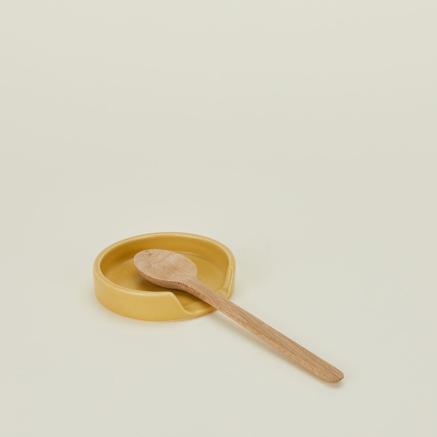 A marigold stoneware spoon rest with a wooden spoon.