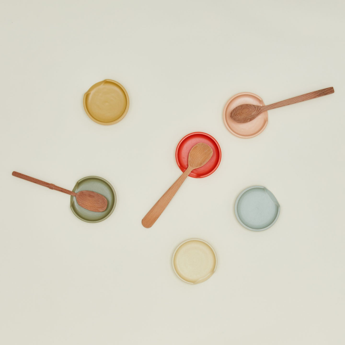 An overhead of spoon rests in various colors with wooden spoons.