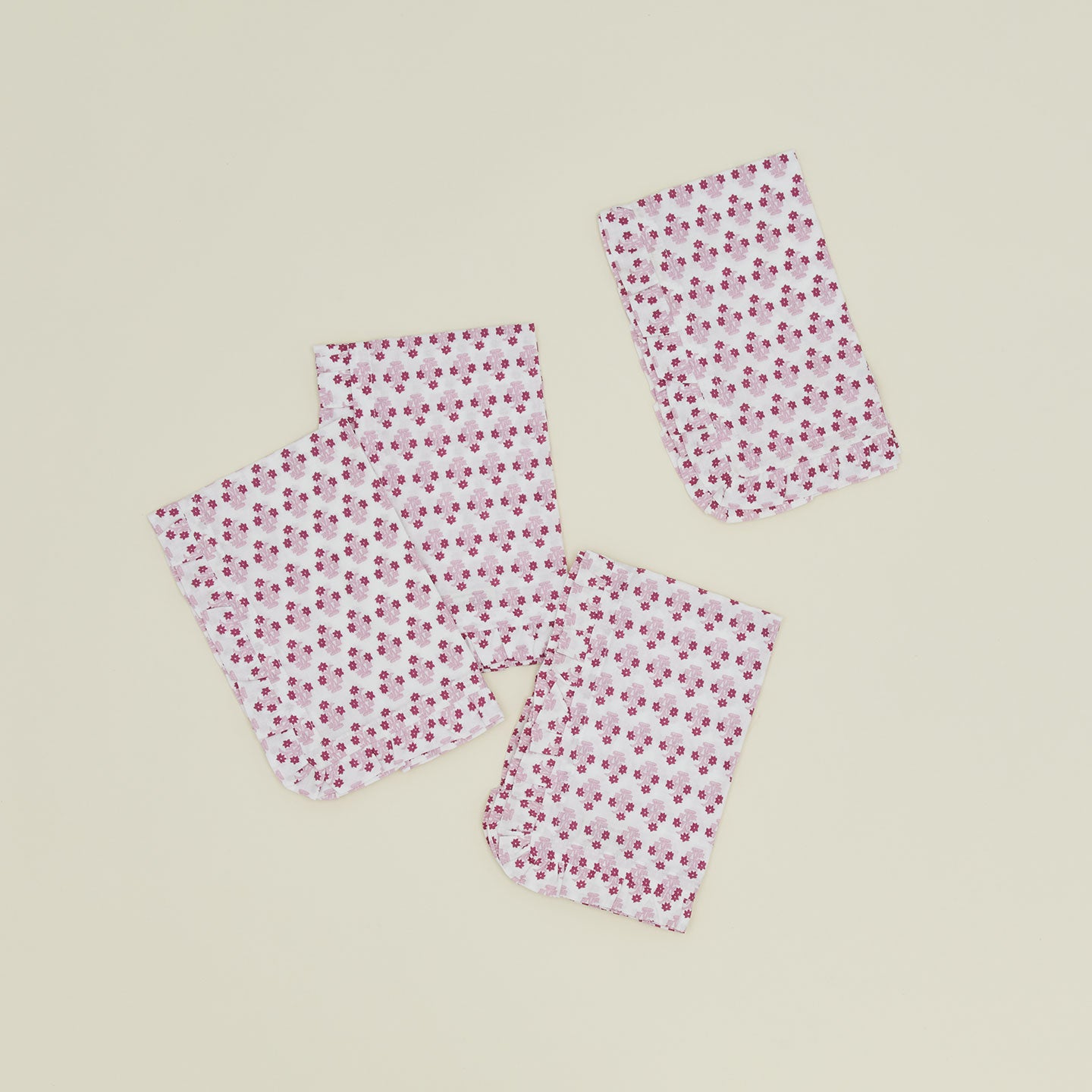 A set of four ruffled dinner napkins with a floral print in Abigail pink.