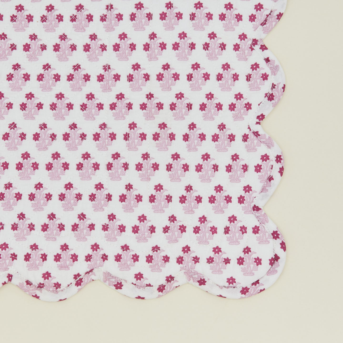 Close up of a quilted placemat with a floral print in Abigail pink.