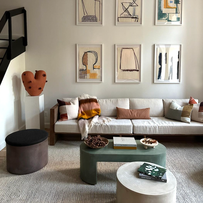 Living room with multiple framed pieces of art, sisal rug, and coffee table with various items