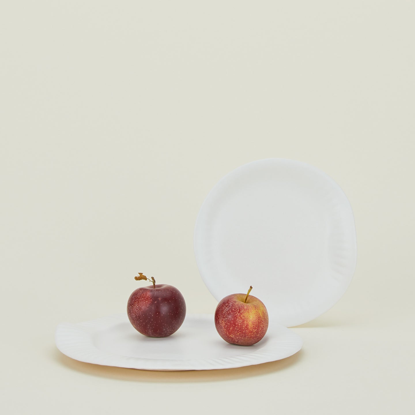 Two porcelain plates with edge texture inspired by paper plates, with fruit.