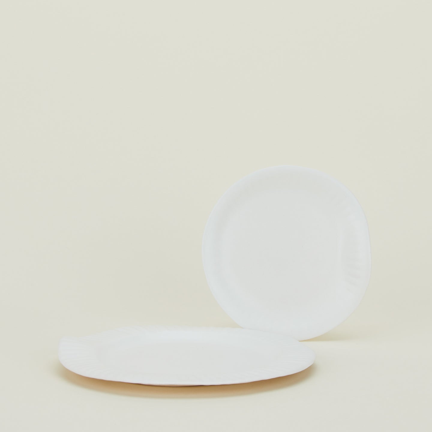 Two porcelain plates with edge texture inspired by paper plates.