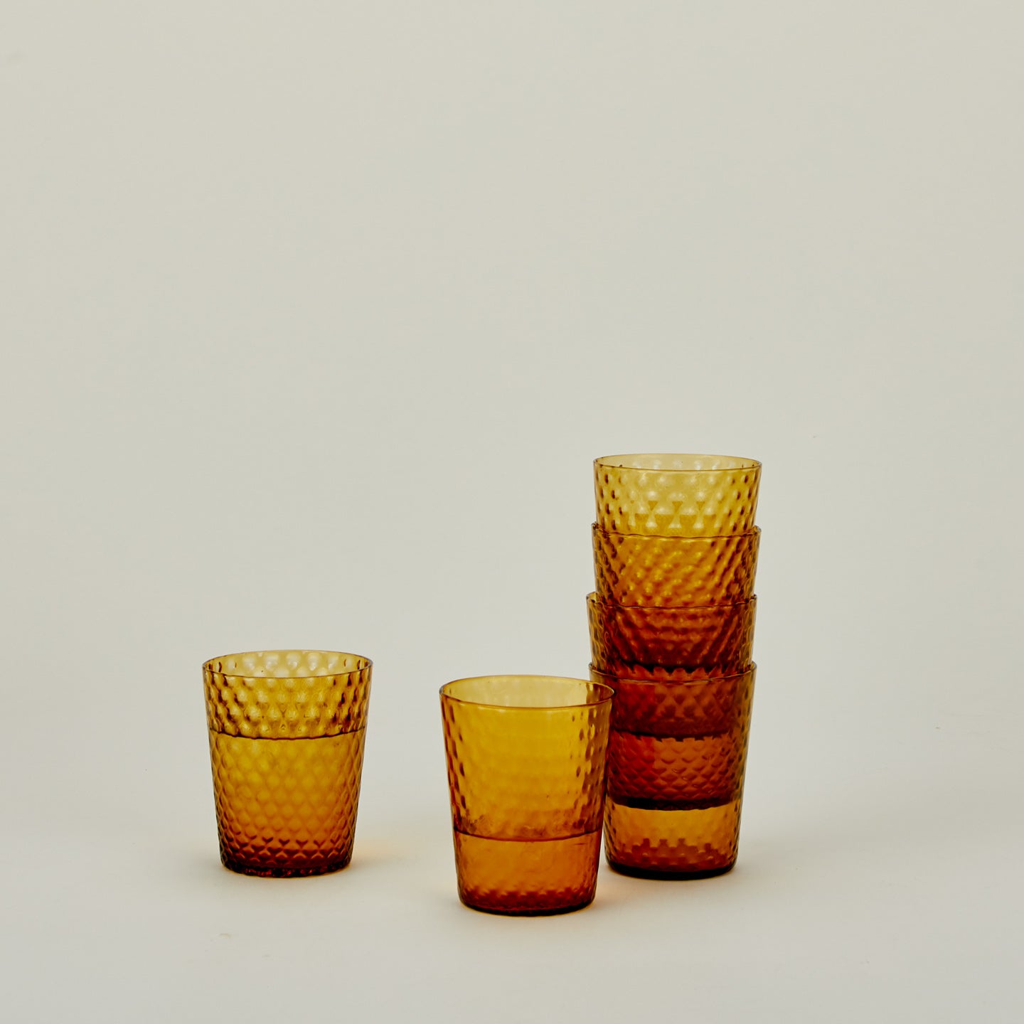 Set of 6 Veneziano Tumblers in Amber, stacked, with water.