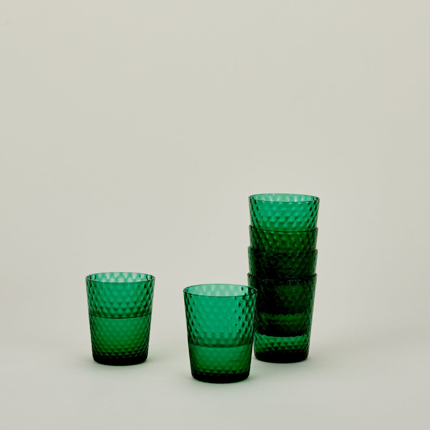 Set of 6 Veneziano Tumblers in Green, stacked, with water.