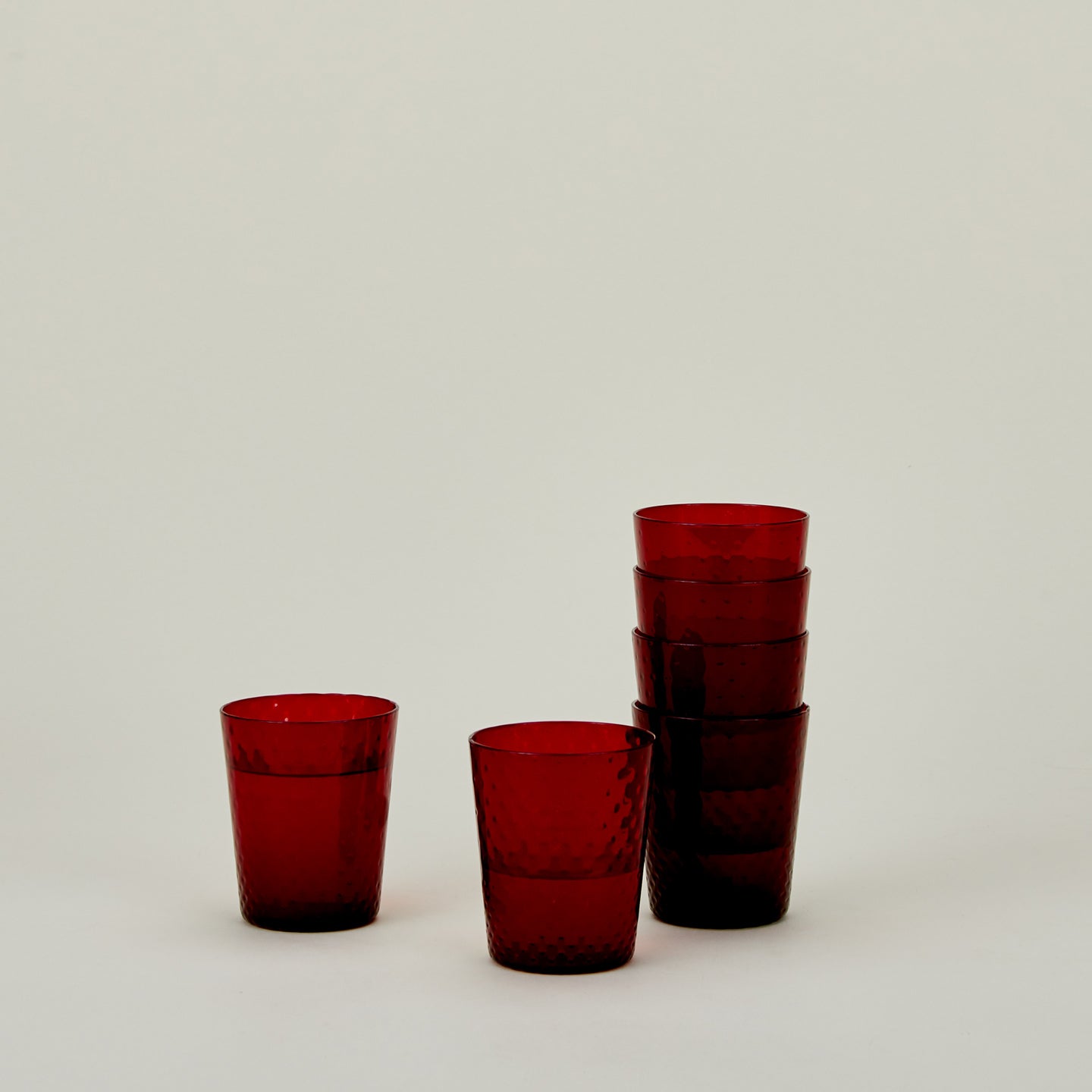 Set of 6 Veneziano Tumblers in Red, stacked, with water.